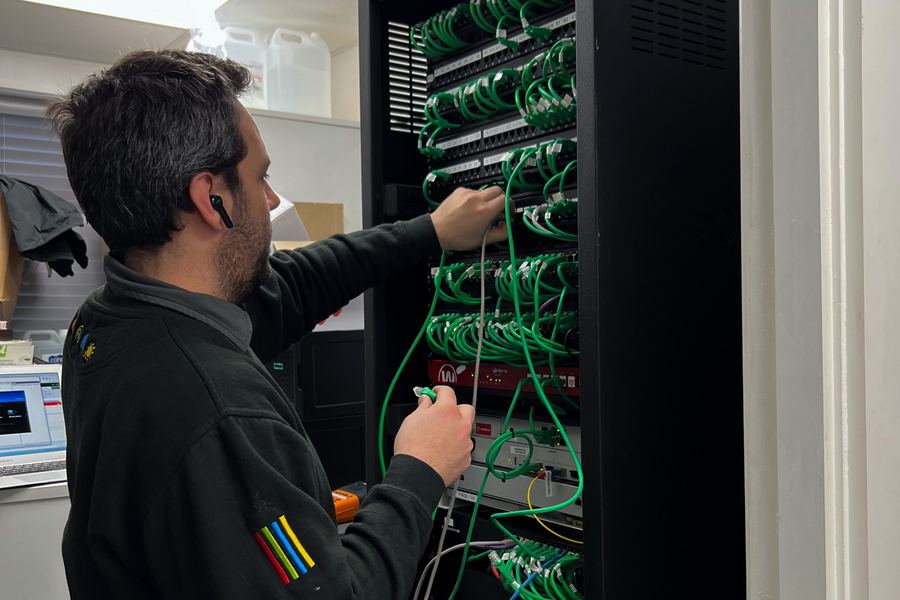 An engineer connecting a venue's network rack